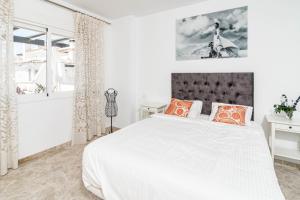 ein weißes Schlafzimmer mit einem großen Bett mit orangefarbenen Kissen in der Unterkunft Spectacular 2 bedroom Penthouse in best location in Nueva Andalucia in Marbella