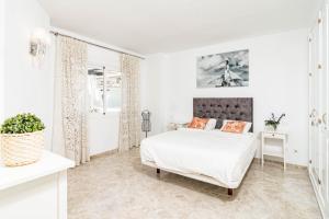 ein weißes Schlafzimmer mit einem Bett mit orangefarbenen Kissen in der Unterkunft Spectacular 2 bedroom Penthouse in best location in Nueva Andalucia in Marbella + 37 Fotos