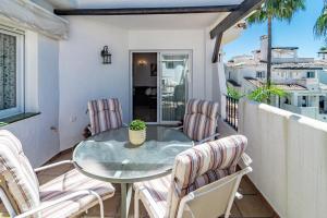 eine Terrasse mit einem Glastisch und Stühlen auf dem Balkon in der Unterkunft Spectacular 2 bedroom Penthouse in best location in Nueva Andalucia in Marbella
