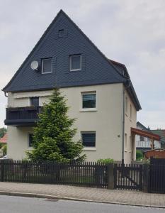 a white house with a black roof and a fence at Ferienwohnung Familie Thiedemann in Pirna
