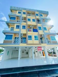 a large yellow building with blue windows at SUKANO Apartment VIP in Ban Thap Nang