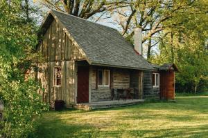 a small wooden cabin with a porch in the grass at Lūķi, Lauku sēta in Jūrkalne
