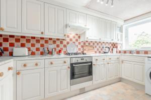 a kitchen with white cabinets and a stove top oven at The Cooperage Garden Apartment - 1 bed-1 bath - near harbour in Crail