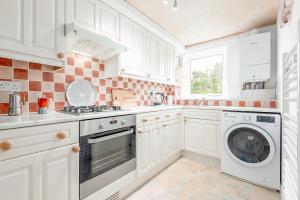 a kitchen with white cabinets and a washer and dryer at The Cooperage Garden Apartment - 1 bed-1 bath - near harbour in Crail