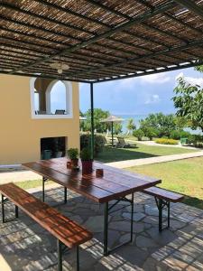 a wooden table and benches under a pergola at Villa Panorama Astrakeri Beach in Astrakeri