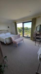 1 dormitorio grande con 1 cama y balcón en Luxurious property set in the heart of Cornwall with breathtaking views -Rhubarb Cottage, en Helston