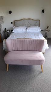 a bed with a pink foot board in a bedroom at Luxurious property set in the heart of Cornwall with breathtaking views -Rhubarb Cottage in Helston