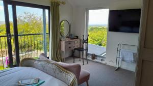 1 dormitorio con balcón con cama y espejo en Luxurious property set in the heart of Cornwall with breathtaking views -Rhubarb Cottage, en Helston