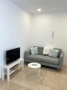 Una sala de estar con un sofá y un televisor de pantalla plana. en 2 Jj e Hijos Conil SL, en Conil de la Frontera