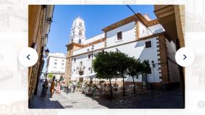 ulica miejska z wieżą zegarową w tle w obiekcie Bonito y luminoso piso en centro histórico de Cádiz w Kadyksie