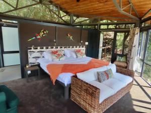 a bedroom with a bed and a couch in a room at Greenfire Game Lodge in Balule Game Reserve
