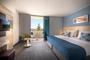 a hotel room with a bed and a balcony at Valamar Diamant Hotel in Poreč