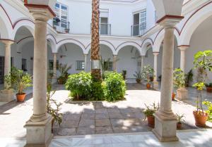 un patio con palmeras y plantas en un edificio en El Patio del Sol, apartamentos Living Sur, en Sanlúcar de Barrameda