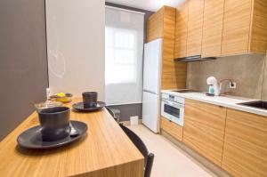 una cocina con una mesa de madera con dos platos. en El Patio del Sol, apartamentos Living Sur, en Sanlúcar de Barrameda