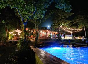 - une piscine avec des lumières dans les arbres la nuit dans l'établissement Nakabalo Guesthouse & Restaurant, à Siquijor