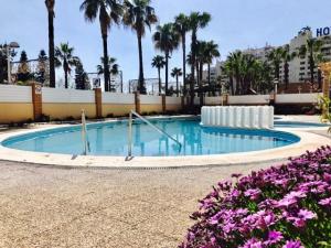 a swimming pool at a resort with purple flowers at Apartamentos Boutique Playa in Cabanes