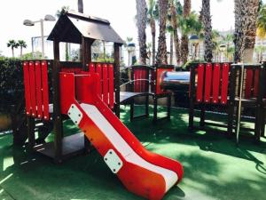 een speeltuin met een rode glijbaan en een prieel bij Apartamentos Boutique Playa in Cabanes