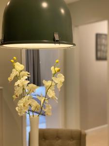 a green lamp with a vase with flowers in it at Apartman Teatar in Sombor