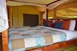 a bedroom with a bed with a quilt on it at Oldarpoi Mara Camp in Keekorok