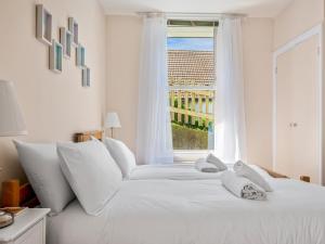 uma cama branca com almofadas brancas e uma janela em Pass the Keys Jarrahdale Beach House - Stunning Luxurious Holiday Pad by the sea em Herne Bay