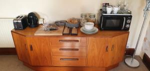 a microwave sitting on top of a wooden cabinet at The Apartment at Pen Y Coed Hall in Dolgellau
