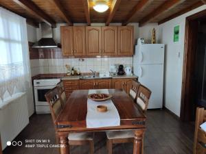 a kitchen with a wooden table and a white refrigerator at Elia house 1 astoning sea view among the olive trees in Patitiri