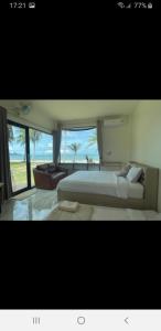 a bedroom with a large bed and a large window at Baan Be Beach in Lang Suan