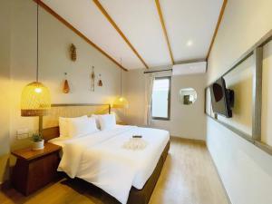 um quarto com uma grande cama branca e uma televisão em BARA BARA' Budget SATUN 'SHA Plus' em Satun
