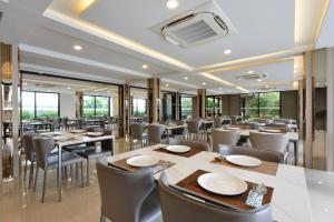 a restaurant with tables and chairs and windows at Grand BS Airport Hotel Suvarnabhumi in Lat Krabang