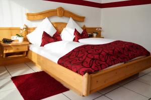 a bedroom with a large bed with a red comforter at Hotel Weinhaus Wiedemann in Ginsheim-Gustavsburg