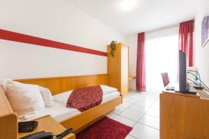 a bedroom with a bed and a desk with a television at Hotel Weinhaus Wiedemann in Ginsheim-Gustavsburg