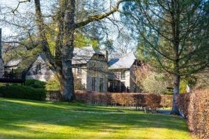 una gran casa de piedra con árboles en el patio en Bovey Castle en Moretonhampstead