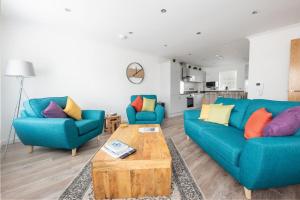 a living room with two blue couches and a coffee table at Modern Ground Floor Apartment in Tornagrain in Inverness