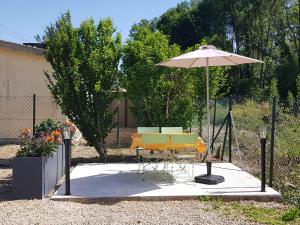 stół i krzesła pod parasolem na patio w obiekcie Agréable petite maison avec jardin et parking w mieście Chamvres