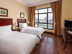 Mercure Grand Hotel Seef - All Suites في المنامة: غرفة فندقية بسريرين ونافذة