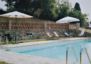 a swimming pool with two umbrellas and a table and chairs at La Fontaiola in Le Piazze