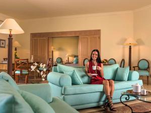 a woman sitting on a couch in a living room at Movenpick Taba Resort & Spa in Taba