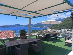 un patio con mesa de madera, sillas y sombrilla en Guest house Villa Slavica, en Sveti Stefan