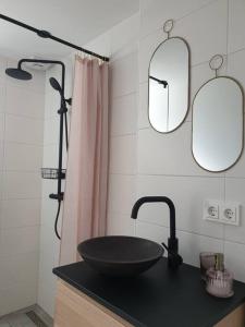 een badkamer met een zwarte wastafel en 2 spiegels bij Het Huisje comfortabel, luxe & sfeervol nabij het strand in Biggekerke