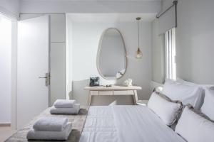 um quarto branco com uma cama e um espelho em Ianthi by Nymphes em Kókkinos Pírgos