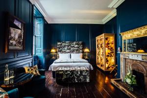 1 dormitorio con paredes azules, 1 cama y chimenea en Bellinter House en Navan