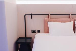 1 cama con almohada blanca y mesa auxiliar en Iliria Boutique Hotel, en Tirana
