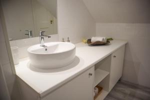 een witte badkamer met een wastafel en een spiegel bij The Residences at Bairro Alto in Lissabon