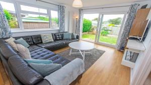 a living room with a leather couch and a table at Swallows Croyde - Open plan beach chalet & close proximity to the beach - Sleeps 6 in Croyde