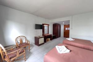 a hotel room with two beds and a chair at Pure Phuket Residence in Phuket