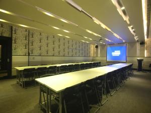 a conference room with tables and chairs and a screen at 冠月精品旅館-Puli Ease Hotel in Puli
