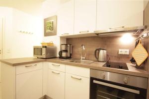 a kitchen with white cabinets and a sink and a microwave at Haus Meeresblick - Ferienwohnung Am Strand (Ref. 128682u1) in Baabe