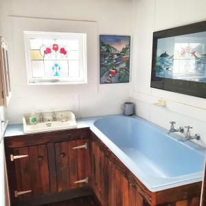 a bathroom with a blue tub and a sink at Walhalla Guesthouses in Walhalla