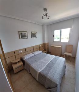 een slaapkamer met een bed en een stoel erin bij Green Beach -2 Dormitorios in Oropesa del Mar