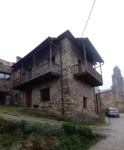 un antiguo edificio de piedra con balcón. en Casa de Abril 2, en San Cristóbal de Valdueza
